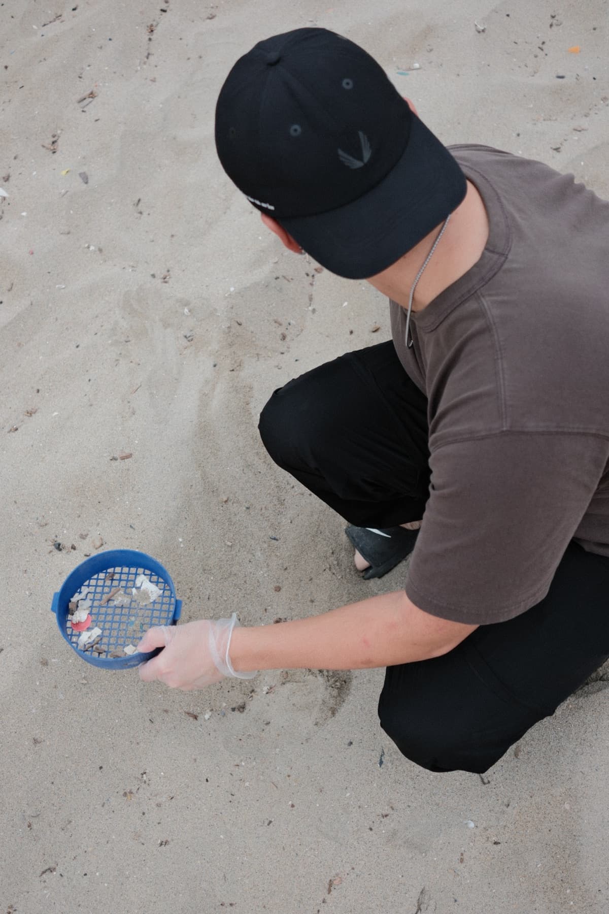 Close view of a 3D-printed cleanup tool collecting beach debris from the sand.